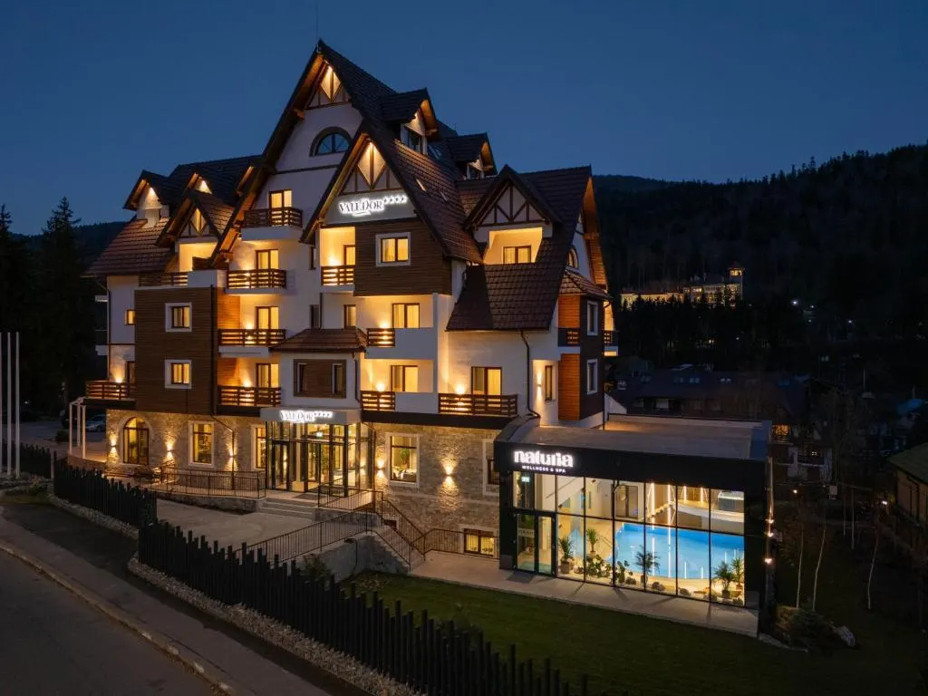 Hotel cu arhitectură de munte, cu fațada iluminată seara