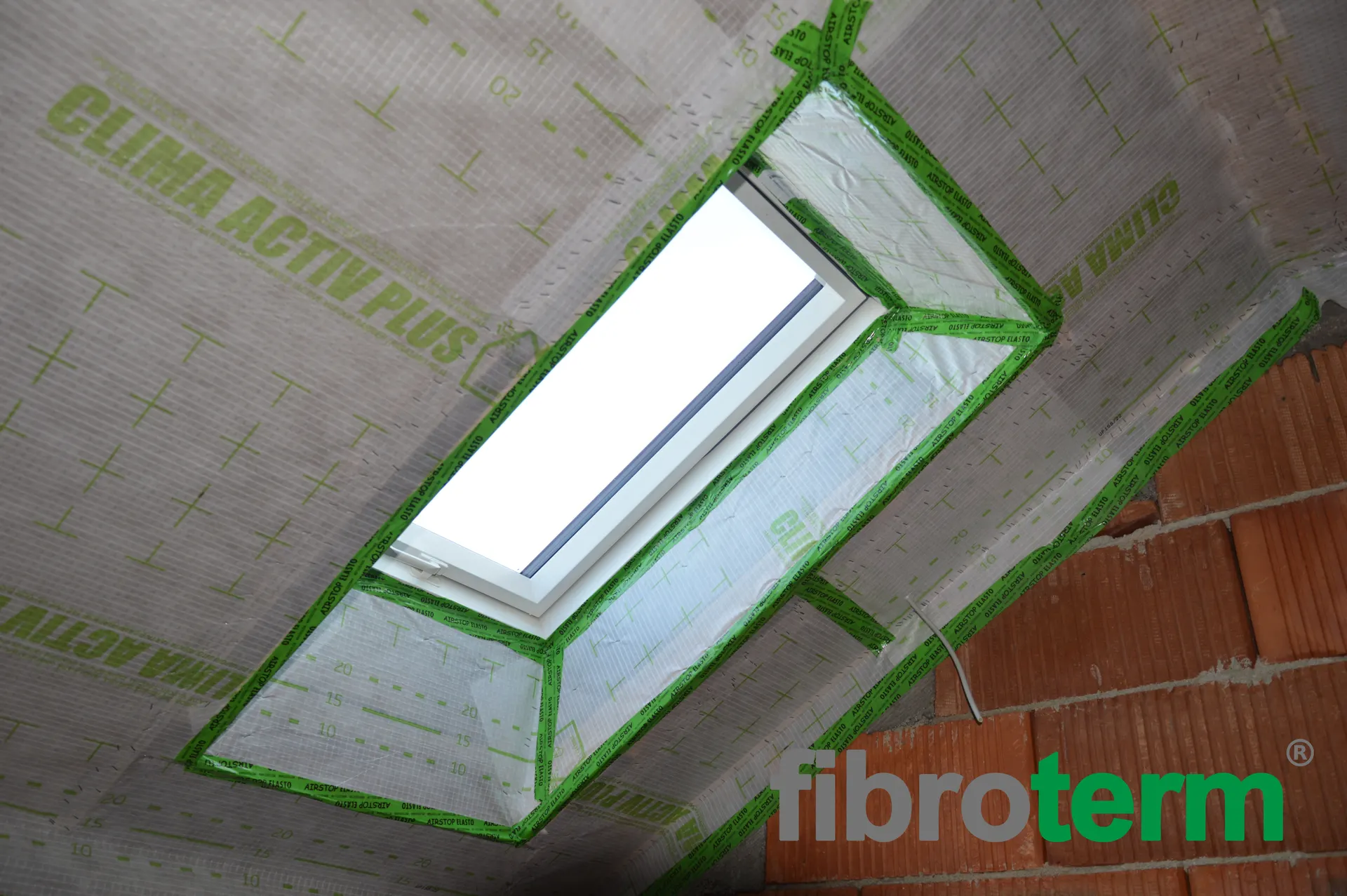 Fereastră de mansardă cu conturul etanșat cu bandă verde pe membrana Clima Activ Plus