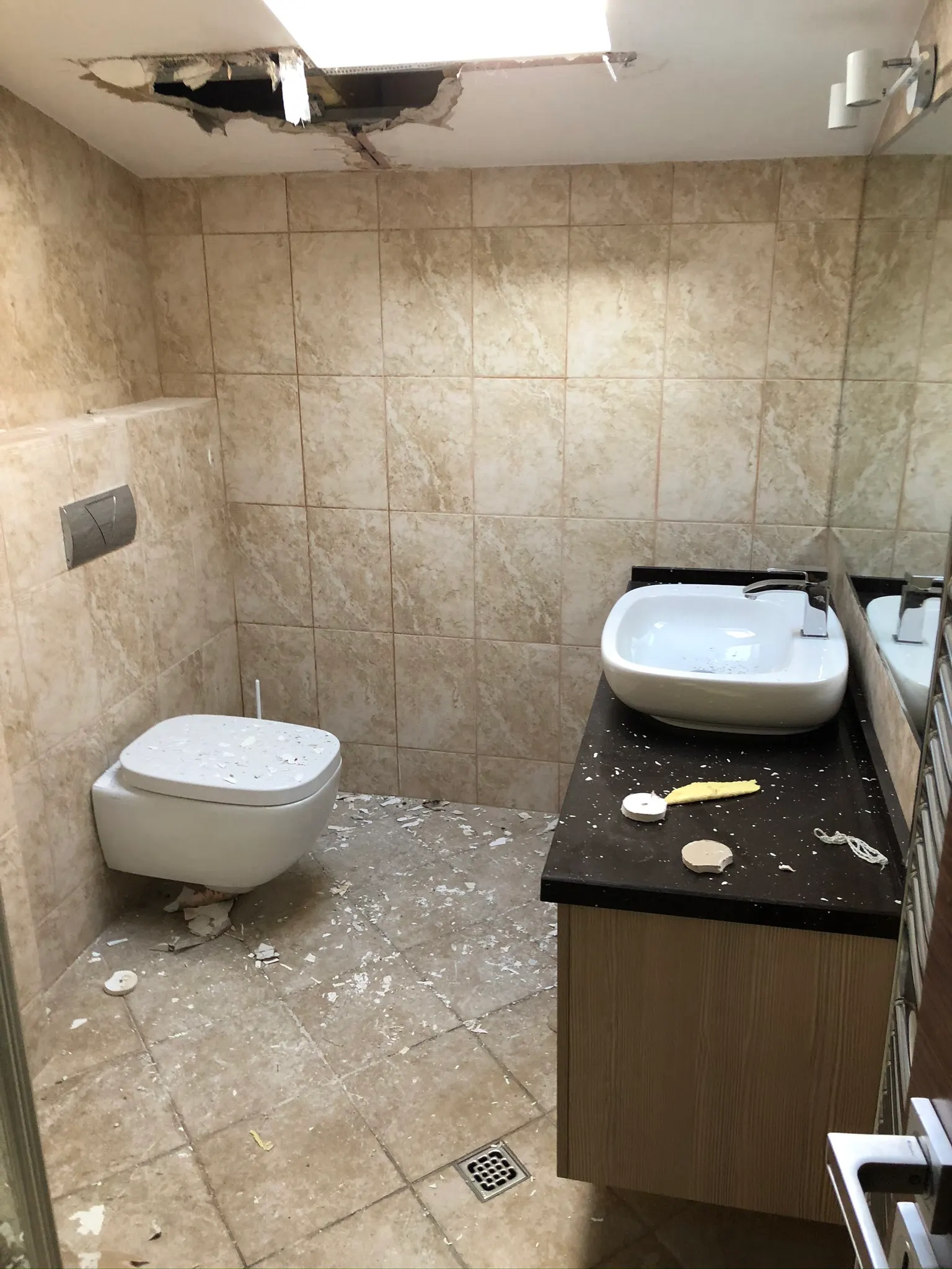 Baie cu o spărtură în tavan și moloz pe pardoseală